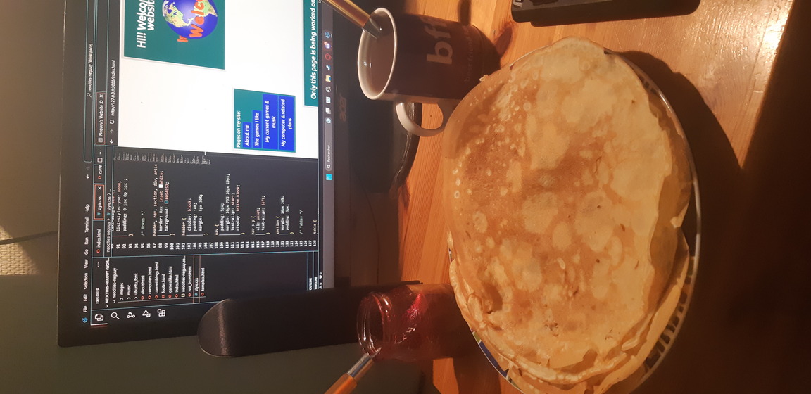 photo: homemade crêpes with a cup of tea and grape jam, all on a desk in front of a monitor showing visual code studio with my site update